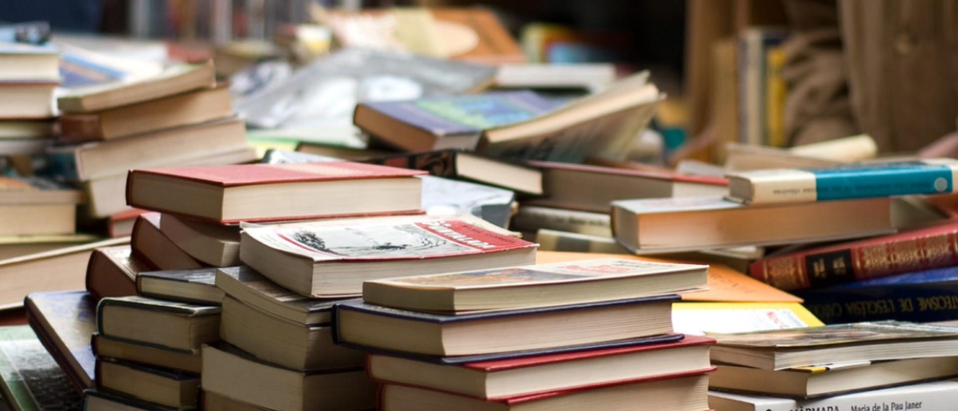 people standing next to pile of books